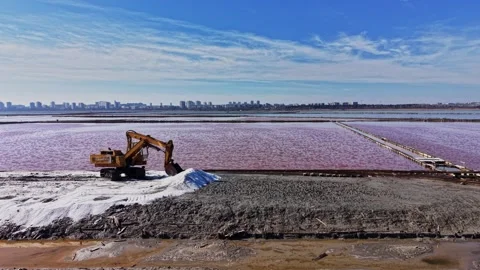 Mining operation at salt mine near city with pink water and machinery Vidéo 337939579