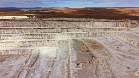 Mining site with large pits and machinery in an open area under a cloudy sky Stock Footage 345455268