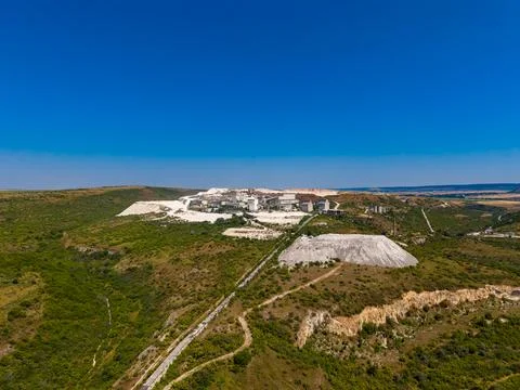A mining site located on hills with greenery. The area has machinery and buil Stock Photos