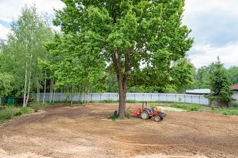 Minitractor on a cultivated plot of land next to a tree Stock Photos