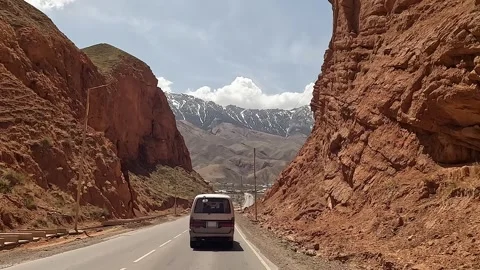 Minivan drives between two high rocks. Beautiful mountain valley Stock Footage 241381309