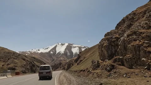 Minivan is driving on a mountain road. View of snow-capped mountains Stock-Footage 241381838