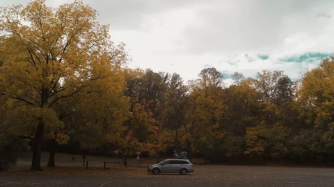 A minivan surrounded by fall leaves while traveling on family vacation Stock Footage 144360470