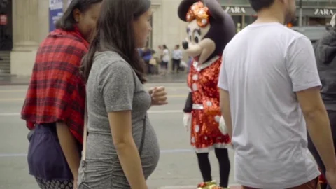 Minnie Mouse and Mickey dancing with little girl on busy crowded Hollywood LA Stock Footage 70685760