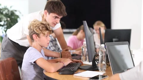 Minor male student learning computer programs excitedly with teacher in training Stock Footage 317532002