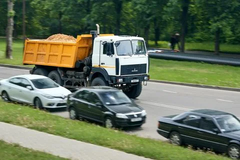 Minsk, Belarus - May 28 2021: MAZ-5516 white heavy dump truck with full orang Stock Photos
