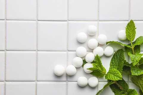 Mint candies. Menthol bonbons and mint leaves on white table. Stock Photos