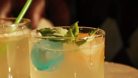 Mint falling down on lemonade with colorfull ice in glass Stock Footage 155792495