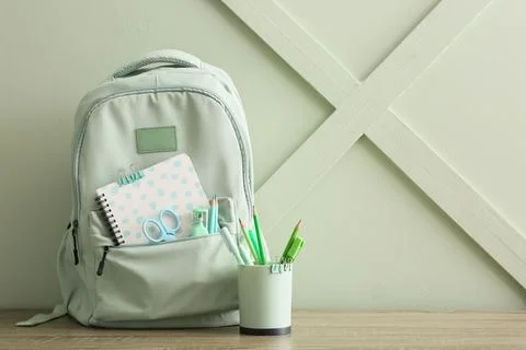 Mint green backpack with school supplies and stationery on a wooden table, ba Stock Photos