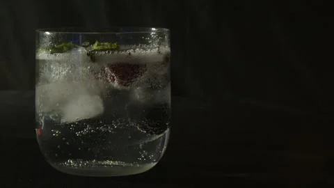 Mint leaves added to fruit soda drink on dark background, close-up Video stock 333798124