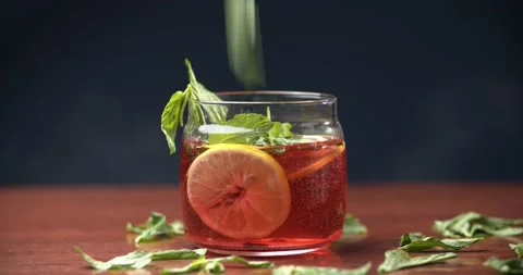 Mint leaves fall into the tea with lemon Stock Footage 147437593