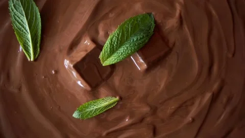 Mint leaves falling into the melted chocolate, slow motion close up shot Stock Footage 131673030