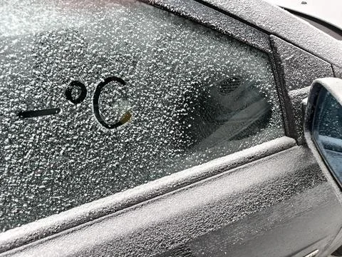 Minus degrees Celsius written on the frozen side window of a car Stock Photos
