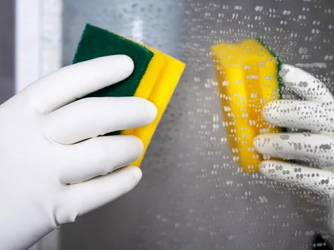 Mirror cleaning process. Hand in a white glove with a yellow sponge in it Stock Photos