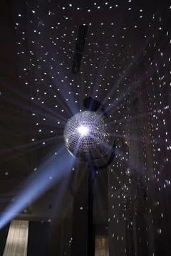 Mirror disco ball reflects light beams and creates a festive atmosphere for a Stock Photos