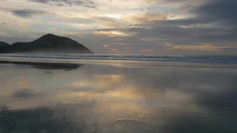 Mirror effect of the sunset on the water on the calm beach, in New Zealand Stock Footage 220295305
