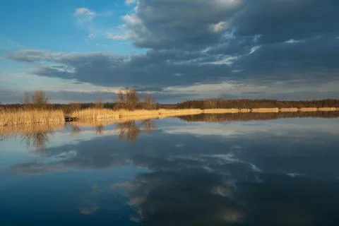 A mirror image of dark clouds in the water of a calm lake Stock Photos