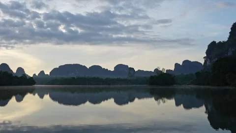 Mirror lake with a reflection blue sky and mountain silhouettes on the water Stock Footage 254281059