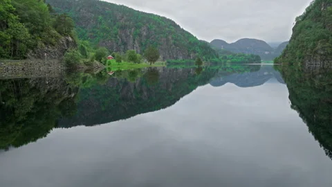 Mirror-like lake surrounded by mountains and Norwegian houses in rural Norway. Stock Footage 328132235
