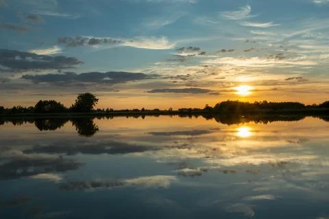 Mirror reflection of clouds in the lake water during sunset Stock Photos