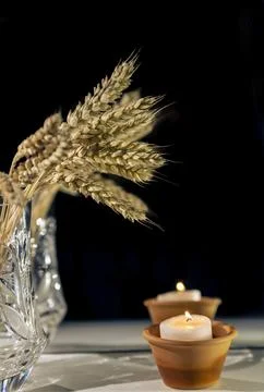 Mirror reflection of ears of wheat and candles on a black background. Stock Photos