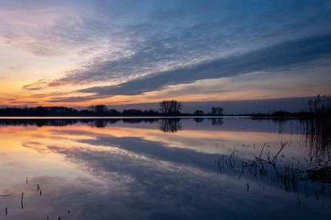 A mirror reflection of the evening clouds in the lake Stock Photos