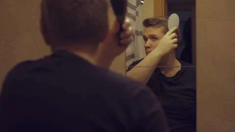 Mirror reflection happy handsome man styling hair Stock Footage 262961572