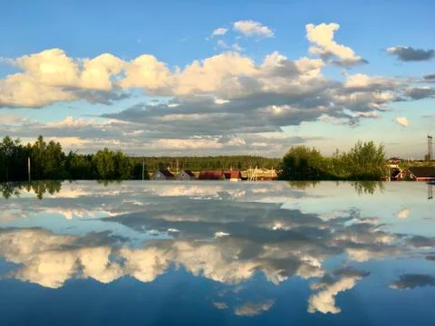 Mirror reflection of pink clouds at sunset on a glass table surface. Stock Photos