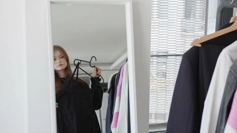 Mirror reflection young woman choosing outfit for workday or date, feeling Stock Footage 237400549