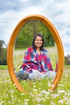 Mirror in spring meadow with sitting pretty woman Stock Photos