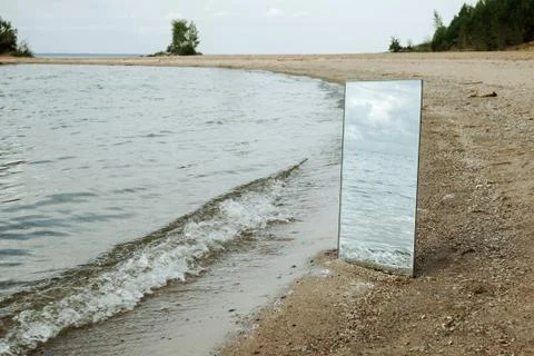 Mirror standing on a beach with waves reflection, selective focus Stock Photos