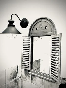 Mirror surrounded by a window with a lamp next to it Foto stock