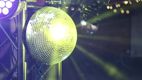 A mirrored disco ball in close-up rotates at a party. Rays of different Video stock 274062064