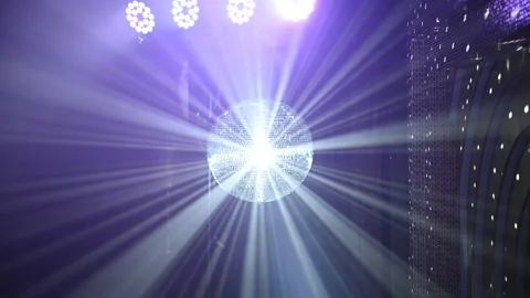 A mirrored disco ball reflects light rays throughout the room. Smoke enhances Stock Footage 305516098