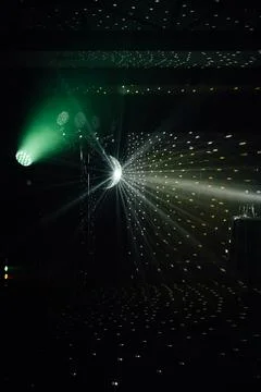 A mirrored disco ball reflects light rays throughout the room. Smoke enhances Stock Photos