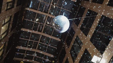 A mirrored disco ball suspended from the ceiling inside a high-rise building. Stock Footage 169235627