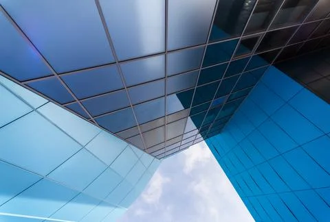 Mirrored windows of the facade of an office building with blue panels and yel Stock Photos