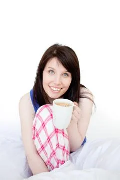 Mirthful woman drinking coffee sitting on bed Stock Photos