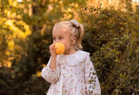 A mischievous and cute child eats a fruit. Pear. Peach. Stock Photos