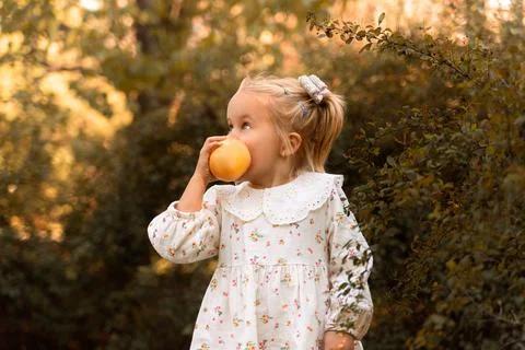 A mischievous and cute child eats a fruit. Pear. Peach. Stock Photos