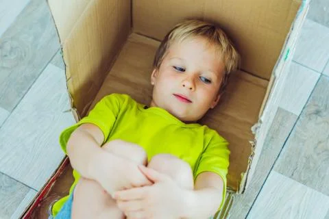 Mischievous boy play hiding in box because does not want to go to school or Foto stock