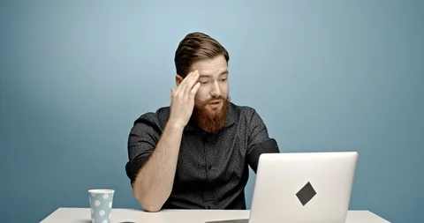 Miserable and bored caucasian young man sitting behind his office desk and Stock Footage 112258382