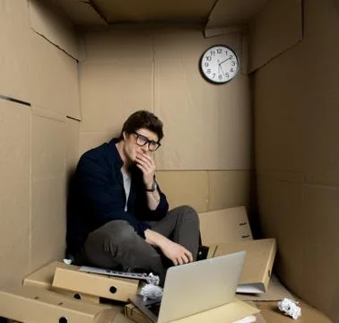 Miserable employee is looking at camera tearfully in cardboard box Stock Photos
