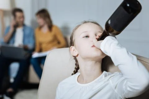 Miserable girl drinking while parents working Stock Photos
