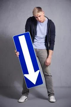 Miserable man holding direction arrow sign pointing down. Stock Photos