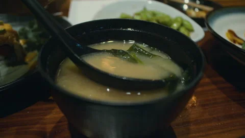 As the miso soup is stirred with serving spoon, pieces of kelp seaweed rise Vídeo Stock 286089520