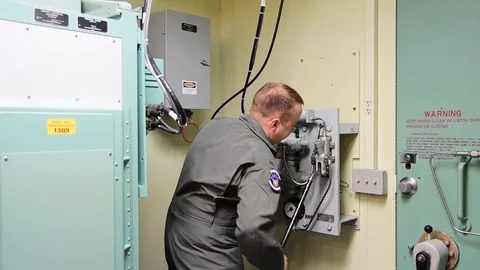 Missile combat crewman operating hydraulic lever in launch control room Stock Footage 111317384