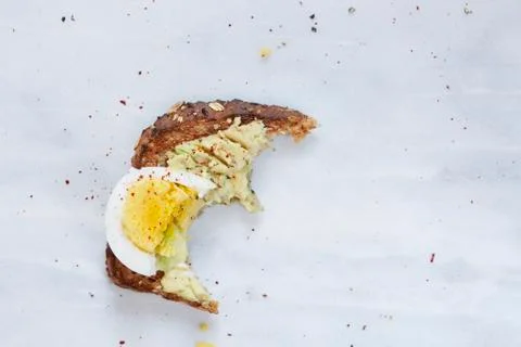 Missing bite of toasted bread with avocado and hard boiled egg Stock Photos