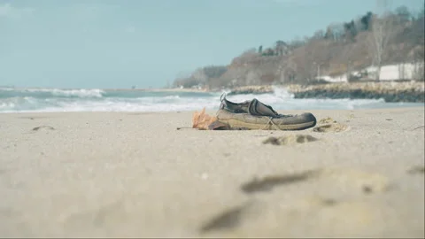 Missing drowned Refugee body rescue mission. Refugee shoe washed up on shoreline Stock Footage 230495611