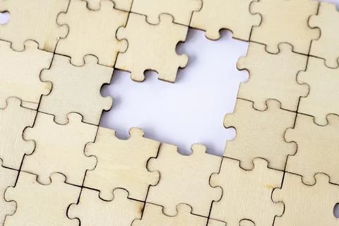 Missing heart-shaped puzzles. A background of puzzles with a white empty space. Stock Photos